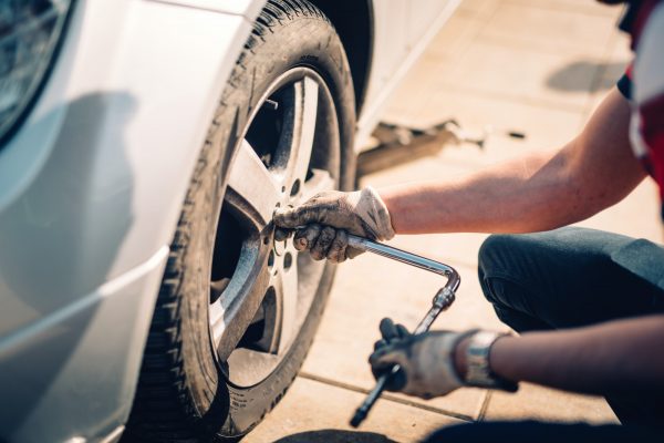 Tire maintenance, damaged car tyre or changing seasonal tires using wrench